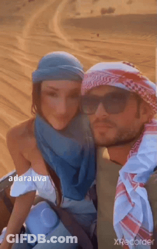 A Man And A Woman Are Posing For A Picture In A Desert . GIF