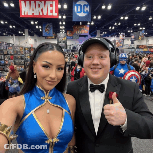 A Man And A Woman Are Posing For A Picture In Front Of A Sign That Says Marvel GIF