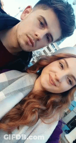 A Man And A Woman Are Posing For A Picture Together And Smiling . GIF