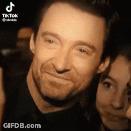 A Man And A Woman Are Posing For A Picture Together And The Man Is Smiling . GIF
