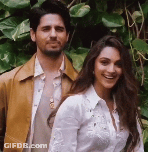 A Man And A Woman Are Posing For A Picture While Standing Next To Each Other . GIF