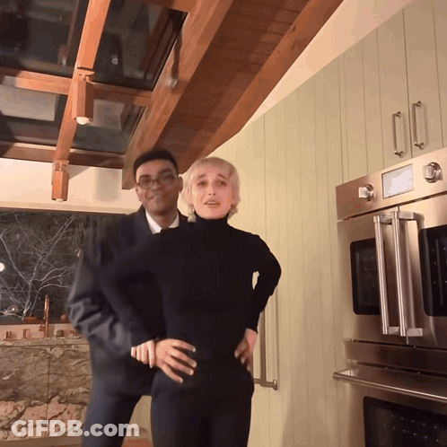 A Man And A Woman Are Posing In A Kitchen GIF