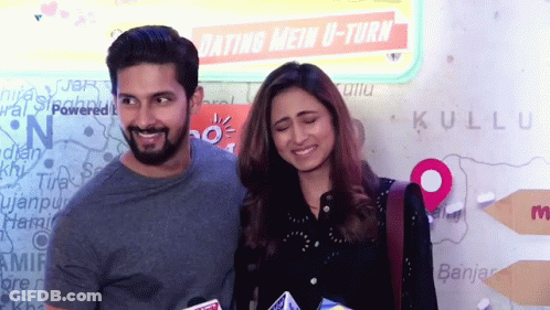 A Man And A Woman Are Posing In Front Of A Sign That Says Dating Mein U-Turn GIF