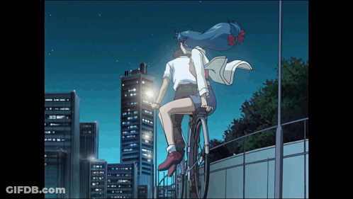 A Man And A Woman Are Riding A Bike In Front Of A City Skyline GIF