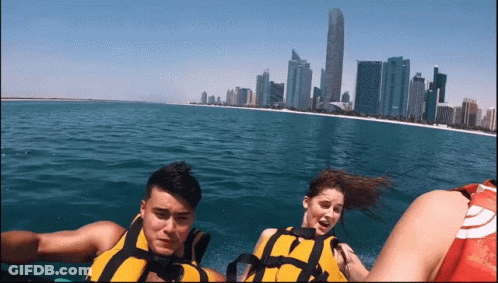 A Man And A Woman Are Riding A Boat In The Ocean GIF