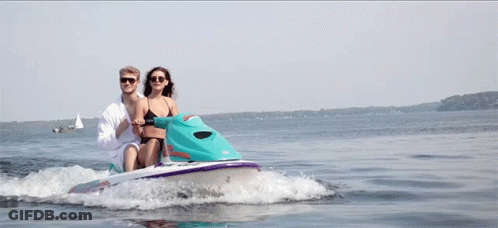 A Man And A Woman Are Riding A Jet Ski With A License Plate That Says Jm 4666 GIF