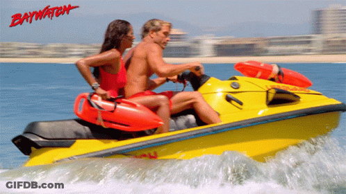 A Man And A Woman Are Riding A Yellow Jet Ski With Baywatch Written In Red GIF