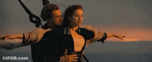 A Man And A Woman Are Riding On The Back Of A Boat . GIF