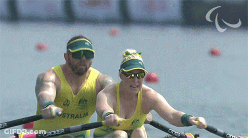 A Man And A Woman Are Rowing In A Boat That Says Australia On The Front GIF