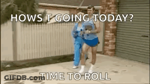 A Man And A Woman Are Running Down A Sidewalk In Front Of A Garage . GIF
