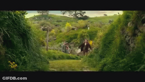 A Man And A Woman Are Running Through A Lush Green Field GIF