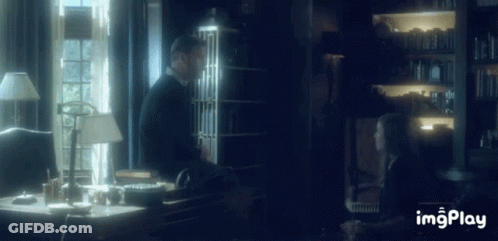 A Man And A Woman Are Sitting At A Desk In A Dark Room With The Words Imgplay Below Them GIF