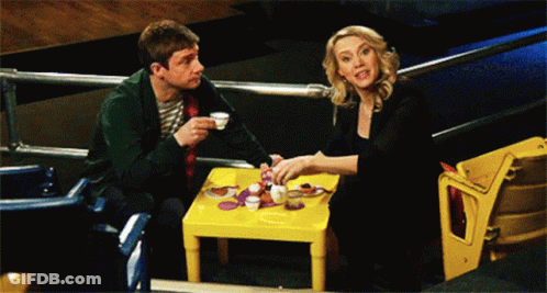 A Man And A Woman Are Sitting At A Small Table GIF