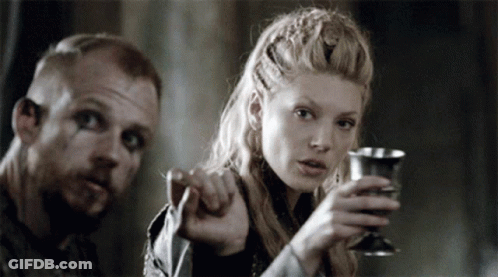 A Man And A Woman Are Sitting At A Table And The Woman Is Holding A Wine Glass GIF