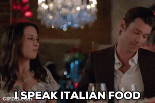 A Man And A Woman Are Sitting At A Table And The Woman Is Saying I Speak Italian Food GIF