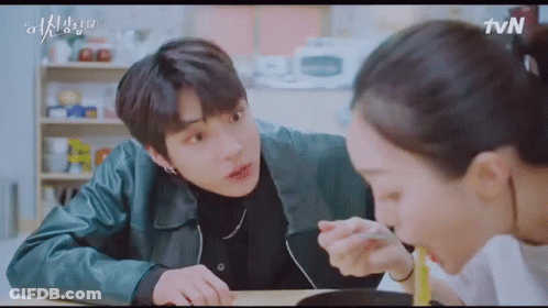 A Man And A Woman Are Sitting At A Table Eating Food Together . GIF