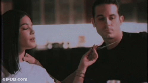 A Man And A Woman Are Sitting At A Table Eating Food With A Fork And Knife . GIF
