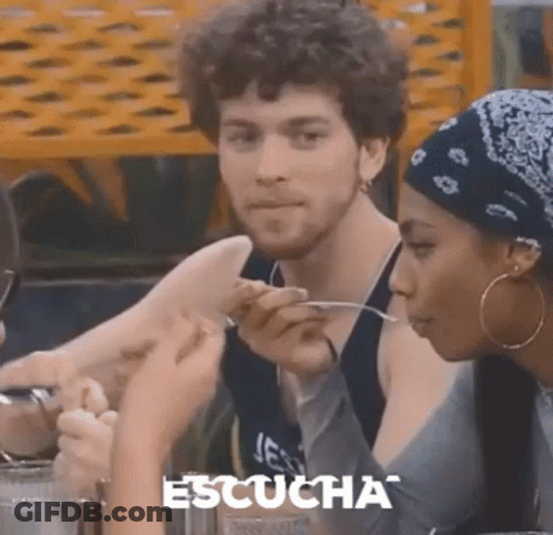 A Man And A Woman Are Sitting At A Table Eating Food With Spoons . GIF