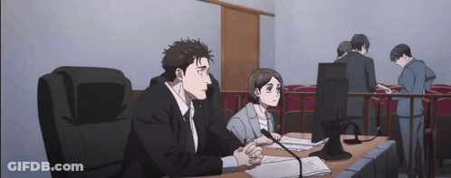 A Man And A Woman Are Sitting At A Table In A Courtroom GIF