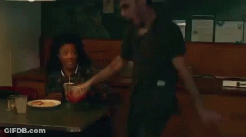 A Man And A Woman Are Sitting At A Table In A Diner Eating Food . GIF
