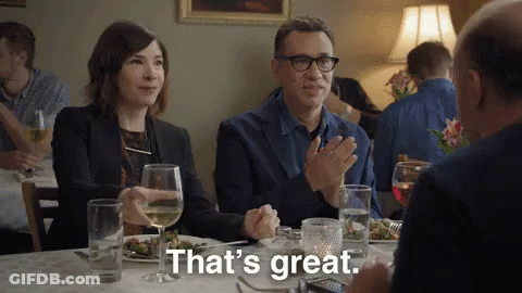 A Man And A Woman Are Sitting At A Table In A Restaurant Applauding And Saying That 'S Great GIF