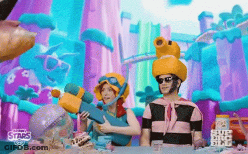 A Man And A Woman Are Sitting At A Table In Front Of A Colorful Background . GIF