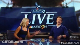 A Man And A Woman Are Sitting At A Table In Front Of A Sign That Says Live GIF