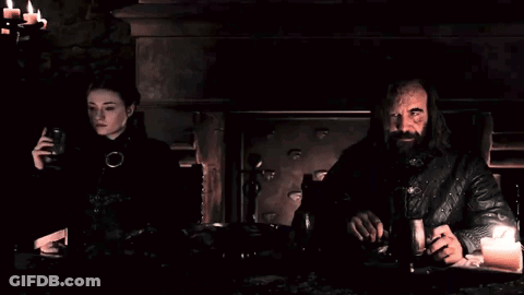 A Man And A Woman Are Sitting At A Table In The Dark GIF