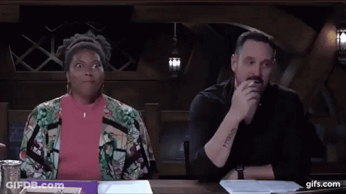 A Man And A Woman Are Sitting At A Table . The Woman Is Making A Funny Face . GIF