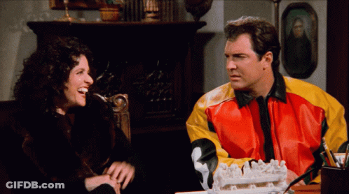 A Man And A Woman Are Sitting At A Table With A Cake In Front Of Them GIF
