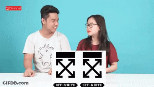 A Man And A Woman Are Sitting At A Table With A Sign That Says Off White GIF