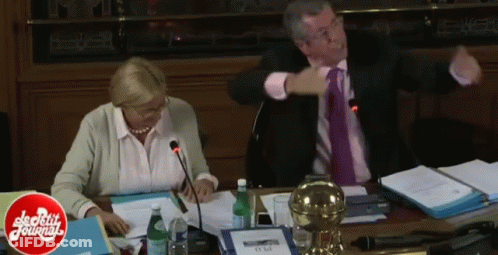 A Man And A Woman Are Sitting At A Table With A Sign That Says ' Strictly Journals ' On It GIF