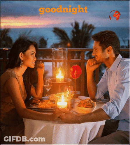A Man And A Woman Are Sitting At A Table With Candles And The Words Goodnight Written Above Them GIF