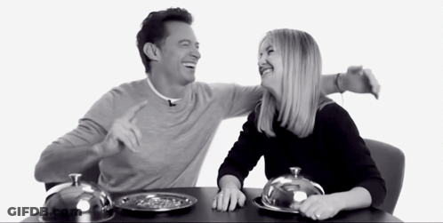 A Man And A Woman Are Sitting At A Table With Plates Of Food On It GIF