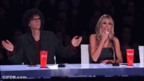 A Man And A Woman Are Sitting At A Table With Red Cups That Say Coca Cola On Them . GIF
