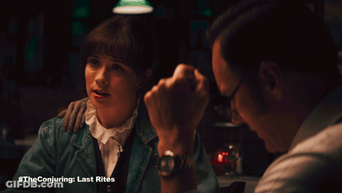 A Man And A Woman Are Sitting At A Table With The Conjuring Last Rites Written On The Bottom GIF