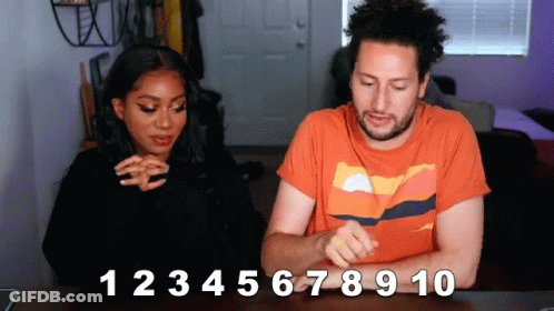 A Man And A Woman Are Sitting At A Table With The Numbers 1 2 3 4 5 6 7 8 9 10 Written On The Table GIF
