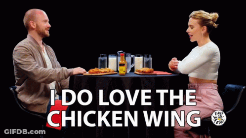 A Man And A Woman Are Sitting At A Table With The Words I Do Love The Chicken Wing On The Bottom GIF