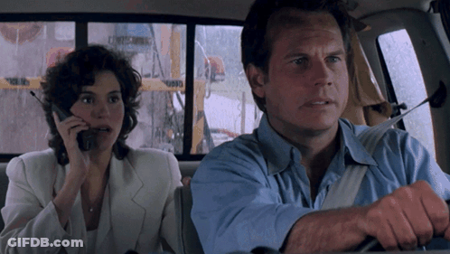 A Man And A Woman Are Sitting In A Car And The Woman Is Talking On Her Phone GIF