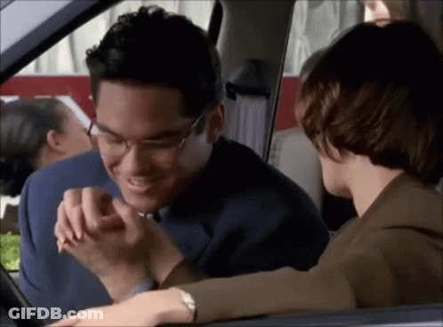 A Man And A Woman Are Sitting In A Car Holding Hands GIF