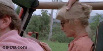 A Man And A Woman Are Sitting In A Car . The Woman Is Wearing Sunglasses And A Pink Shirt . GIF