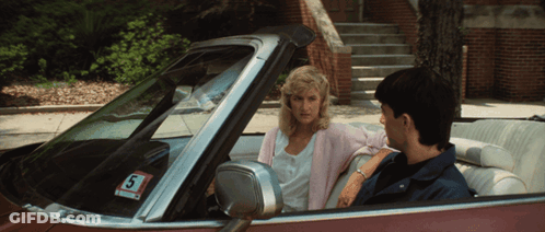 A Man And A Woman Are Sitting In A Car With A Sticker That Says S On It GIF