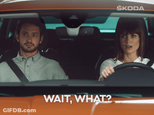 A Man And A Woman Are Sitting In A Car With The Words Wait What On The Bottom GIF