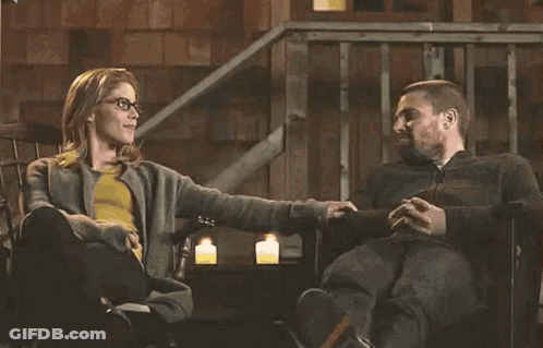 A Man And A Woman Are Sitting In A Chair Holding Hands . GIF