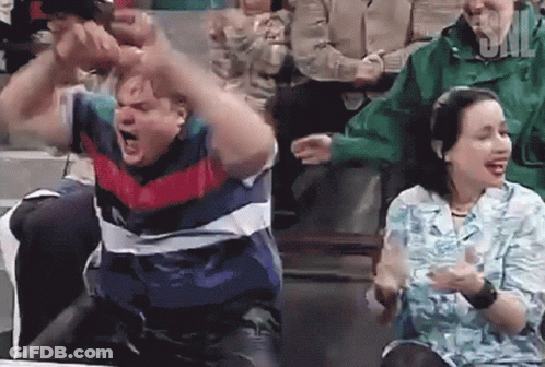 A Man And A Woman Are Sitting In A Crowd And The Man Is Screaming GIF
