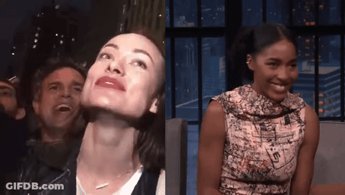 A Man And A Woman Are Sitting In A Crowd And The Woman Is Smiling GIF
