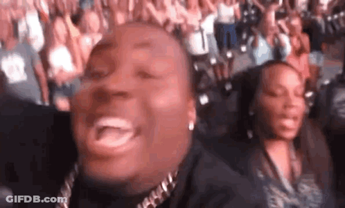A Man And A Woman Are Sitting In A Crowd Of People . GIF