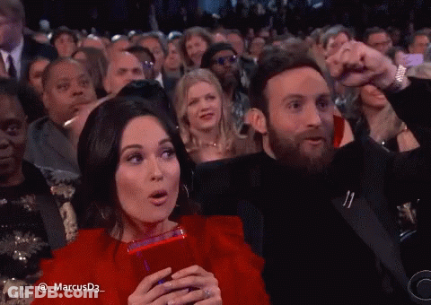 A Man And A Woman Are Sitting In A Crowd With The Name Marcusd3 On The Bottom GIF