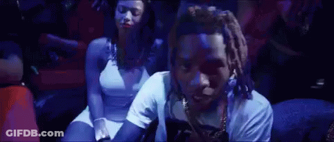 A Man And A Woman Are Sitting In A Dark Room With A Blue Light Behind Them . GIF