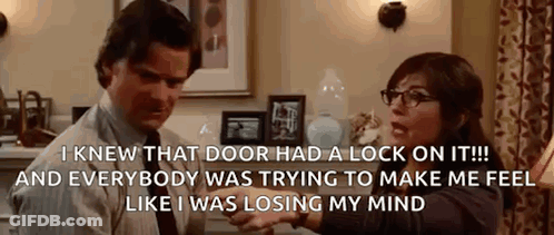 A Man And A Woman Are Sitting In A Living Room Talking To Each Other . The Woman Is Wearing Glasses . GIF